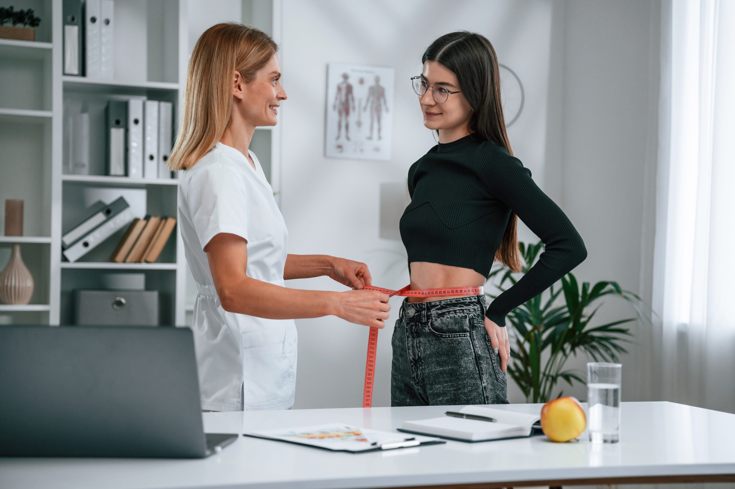 Conception of diet, gain weight, measuring the waist. Young woman at a nutritionist’s appointment. Medical care