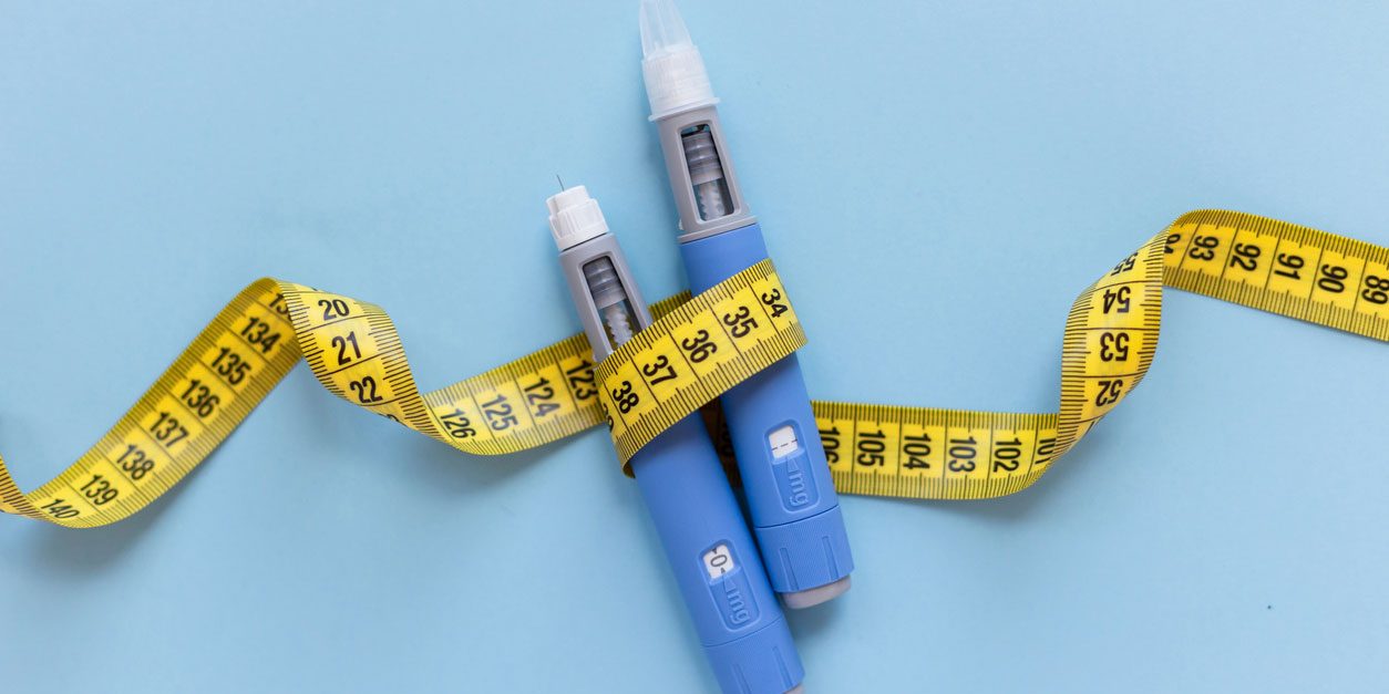 Two injectors dosing pens for anti-obesity medication and yellow measuring tape