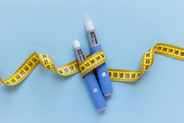 Two-injectors-dosing-pens-for-anti-obesity-medication-and-yellow-measuring-tape Two injectors dosing pens for anti-obesity medication and yellow measuring tape