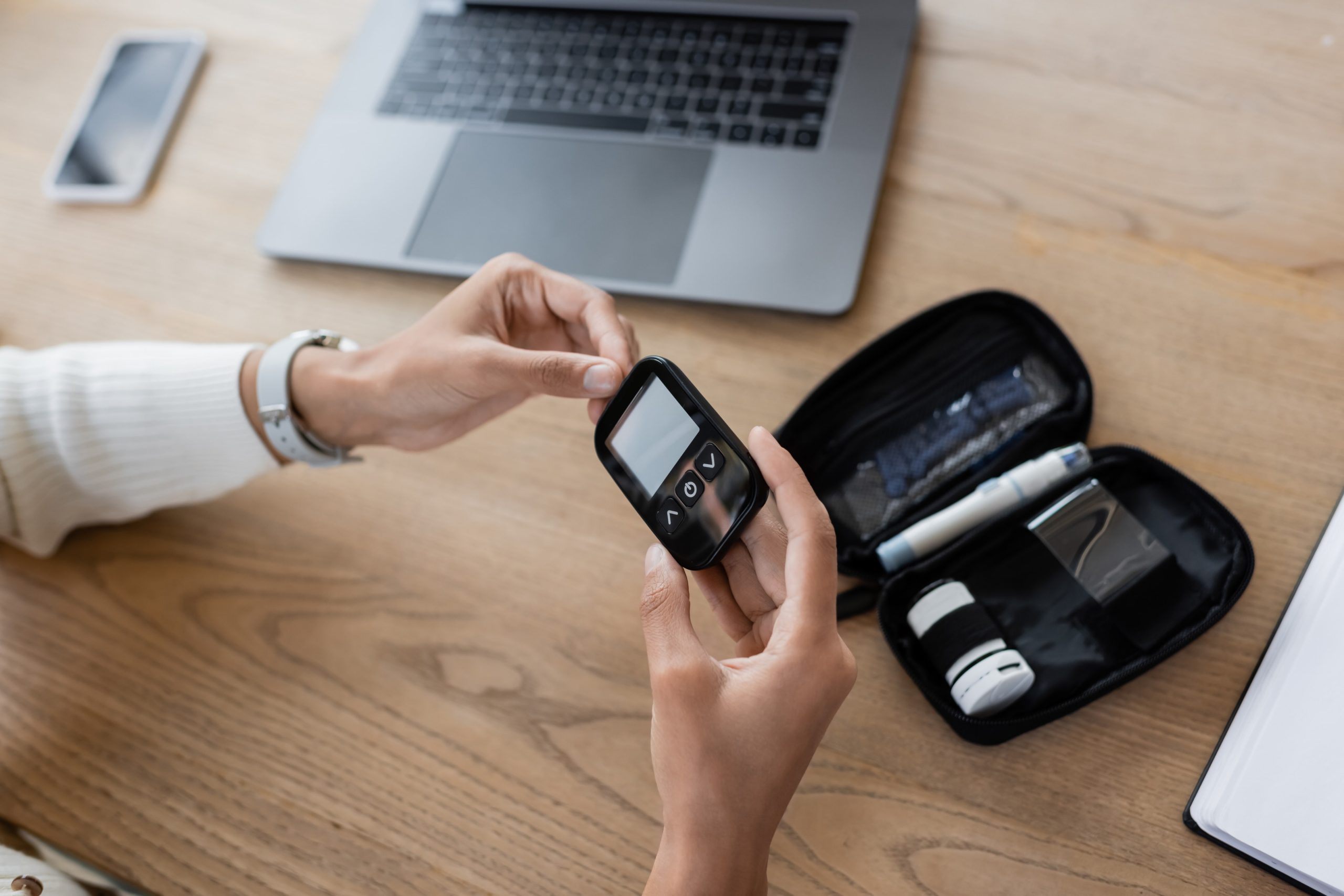 Woman using continuous glucose monitor device at home desk