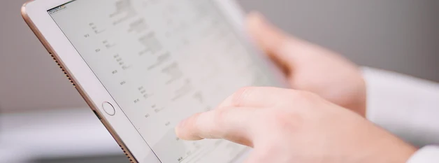 Close-up of hands using a tablet to review digital medical records