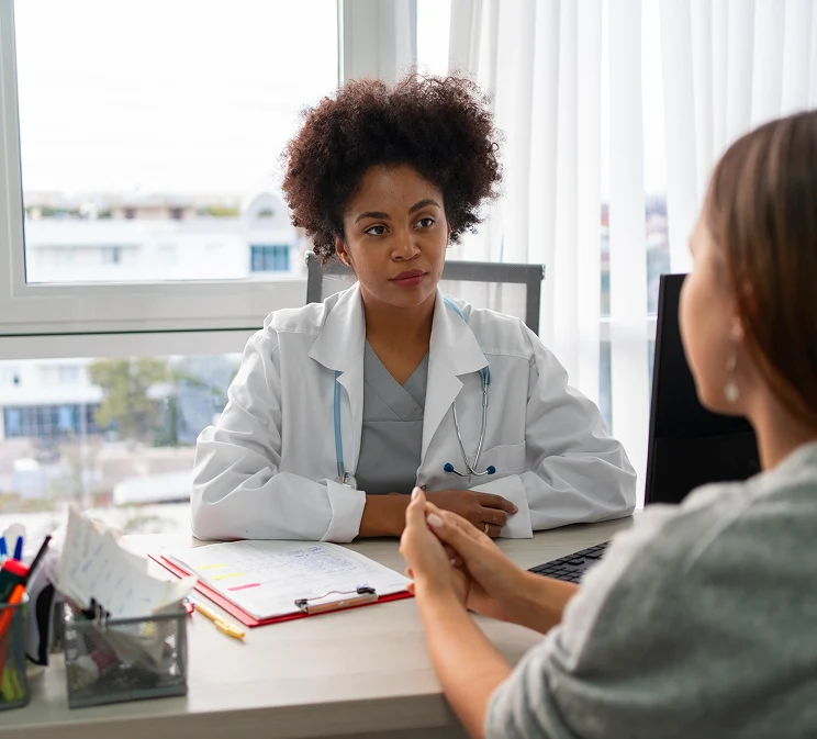Doctor discussing health concerns with a female patient at a desk in a modern clinic.