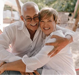 Smiling elderly couple hugging outdoors, showing love, happiness, and long-term companionship.