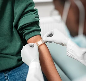 Healthcare worker applying a bandage to a patient’s arm after a medical procedure.