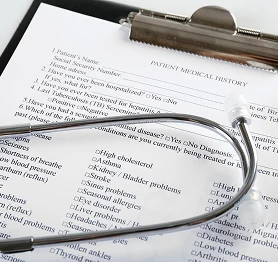 Clipboard with a patient medical history form and stethoscope on a desk in a clinic.