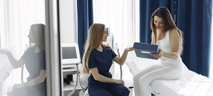 Medical professional reviewing a folder with a patient seated on a treatment table in a clinic