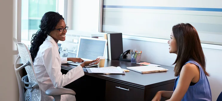 Doctor smiling and consulting with a patient at a desk in a medical office