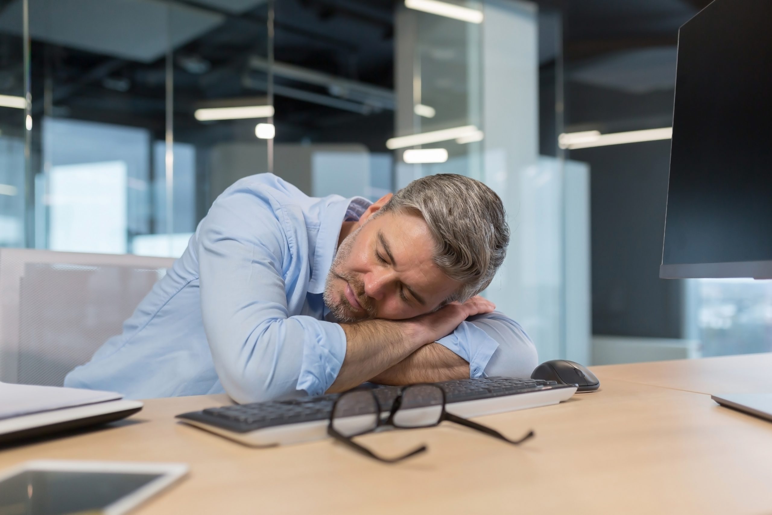 Tired senior boss businessman sleeping on desktop in office